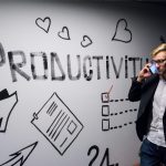 employees' productivity A person walking past a wall that says productivity in black letters