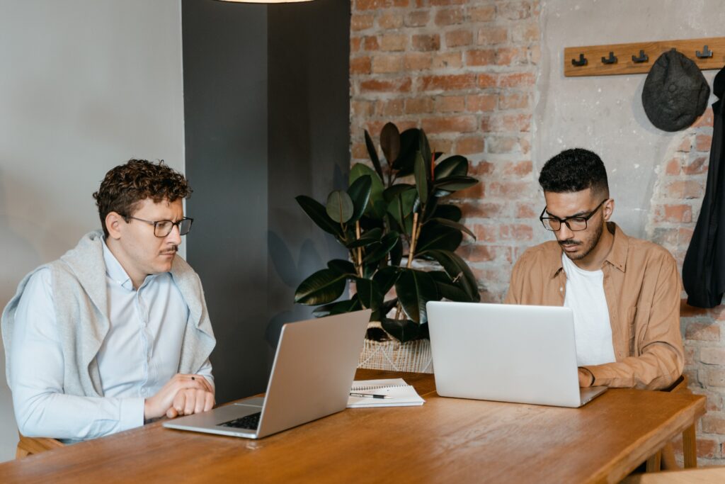 two people working on laptops: text to video creation