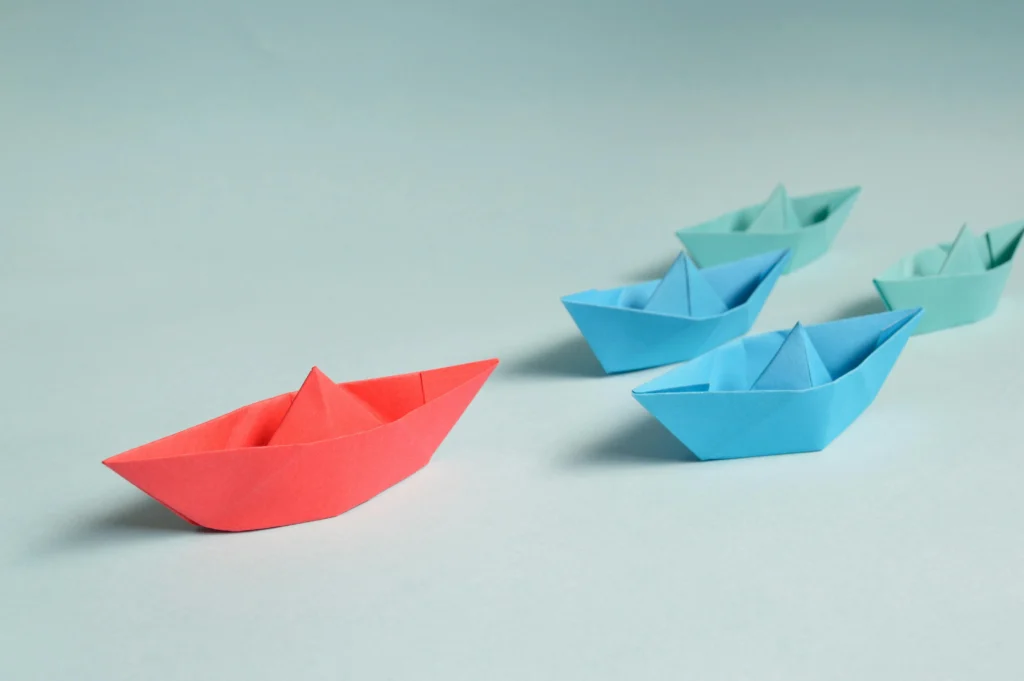 business management: blue boats following a red ship