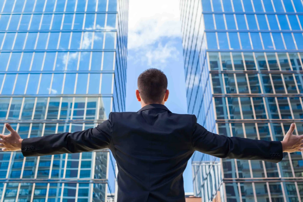 successful man in suit embracing skyscrapers